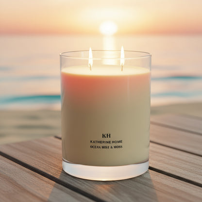 Ocean Mist & Moss candle glowing at sunset on a wooden surface, evoking a calm, seaside mood.