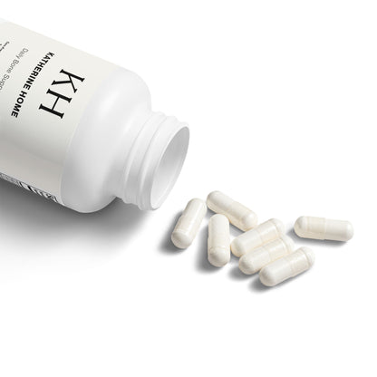 Katherine Home Vitamin K2 + D3 bottle open with capsules spilling gently onto a white surface.